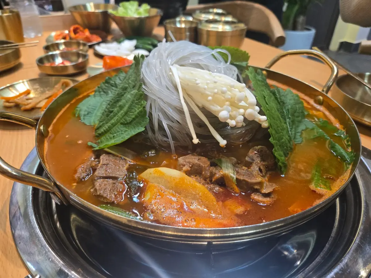 Nồi canh xương heo hầm khoai tây gamjatang sôi lục bục, nước dùng đỏ cay