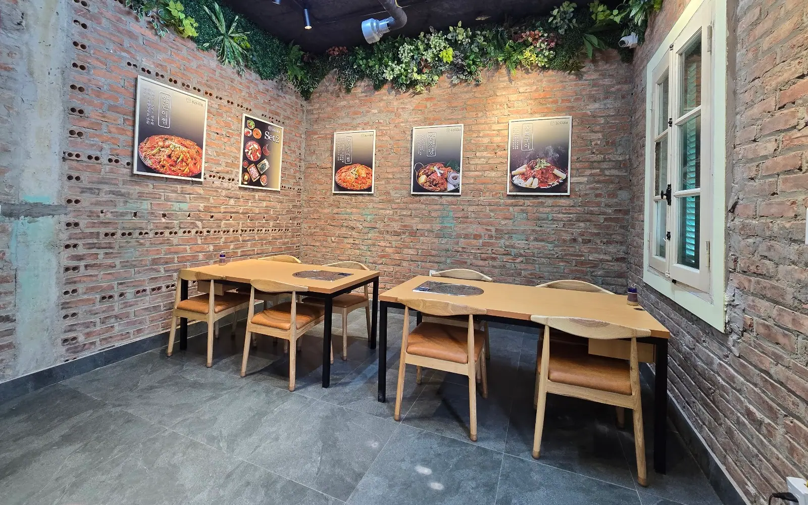 Không gian trong nhà hàng Joseon Sidae — bàn gỗ, tường gạch mộc và ánh đèn ấm