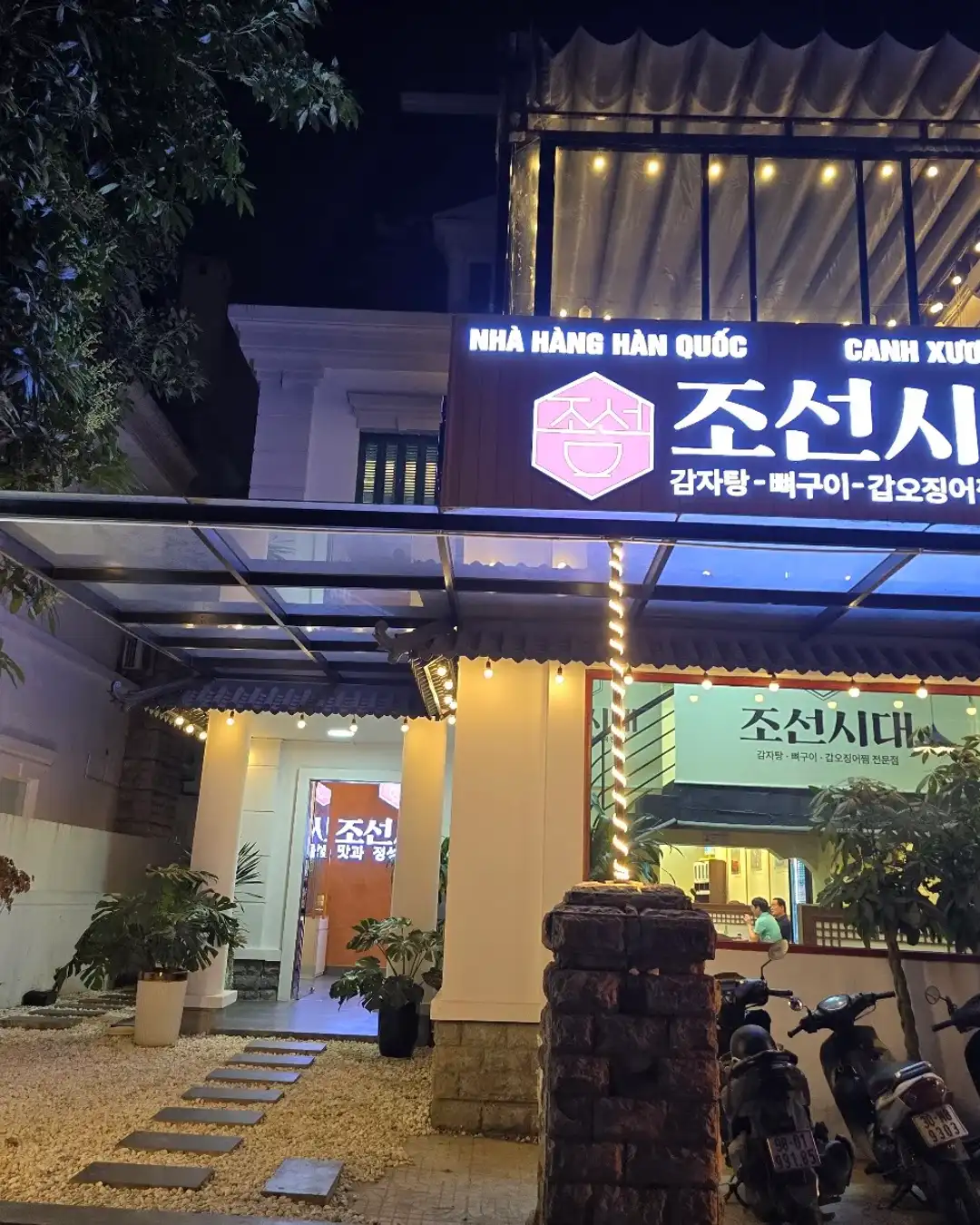 Mặt tiền nhà hàng Joseon Sidae rực sáng về đêm với biển hiệu chữ vàng 조선시대